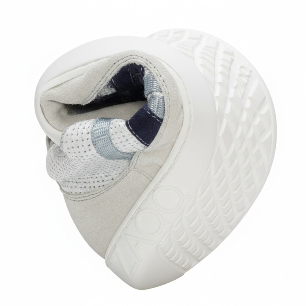 Der DRAQE White Grey Sneaker von ZAQQ verfügt über ein weißes, aufwendig gefaltetes Design, ergänzt durch eine dicke Sohle mit strukturierten blauen und grauen Akzenten. Er ist aus hochwertigem Nappaleder gefertigt und der Markenname ZAQQ ist auf der Seite eingeprägt. Dieser kreativ geformte Schuh ähnelt einem spiralförmigen Design und bietet gleichzeitig den Komfort eines Barfußschuhs.