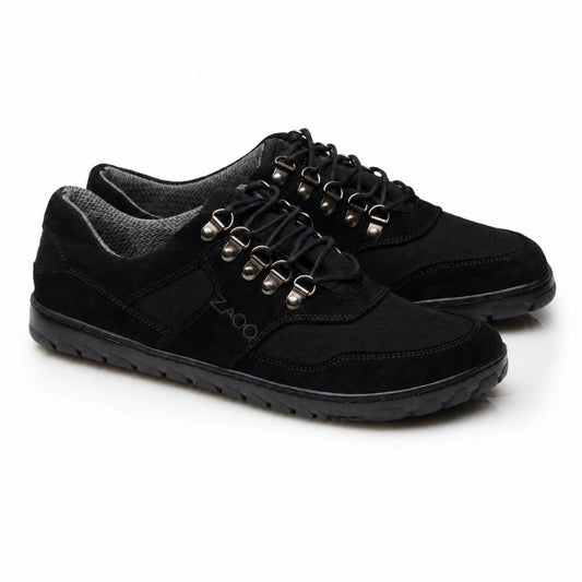 Die HIQE Low Black Waterproof-Schuhe von ZAQQ haben schwarze Schnürsenkel, silberne Ösen und eine Outdoor-Sohle. Ihre strukturierte Sohle passt perfekt zu einer Mischung aus glatten und wildlederähnlichen Materialien im oberen Teil. Der Markenname ZAQQ ist an der Seite deutlich sichtbar.