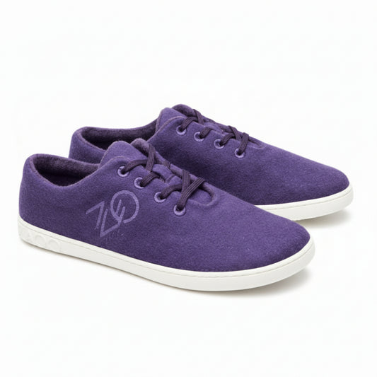 Ein Paar LIQE Purple-Sneaker von ZAQQ mit weißen Gummisohlen und passenden lila Schnürsenkeln. Diese Schuhe zeichnen sich durch ein einzigartiges Logo an der Seite und ein strukturiertes Design an der Ferse für zusätzliches Flair aus.