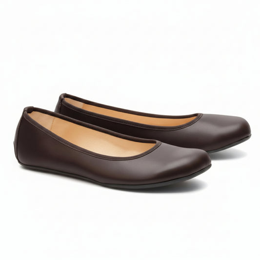 Ein Paar elegante dunkelbraune QARMA-Ballerinas von ZAQQ, wobei ein Schuh auf der Seite liegt, sodass die Sohle sichtbar ist, und der andere aufrecht steht, um die abgerundete Spitze und das tief ausgeschnittene Design hervorzuheben. Das hellbraune Innenfutter verleiht diesen von Barfuß-Ballerinas inspirierten Ballerinas eine elegante Note.