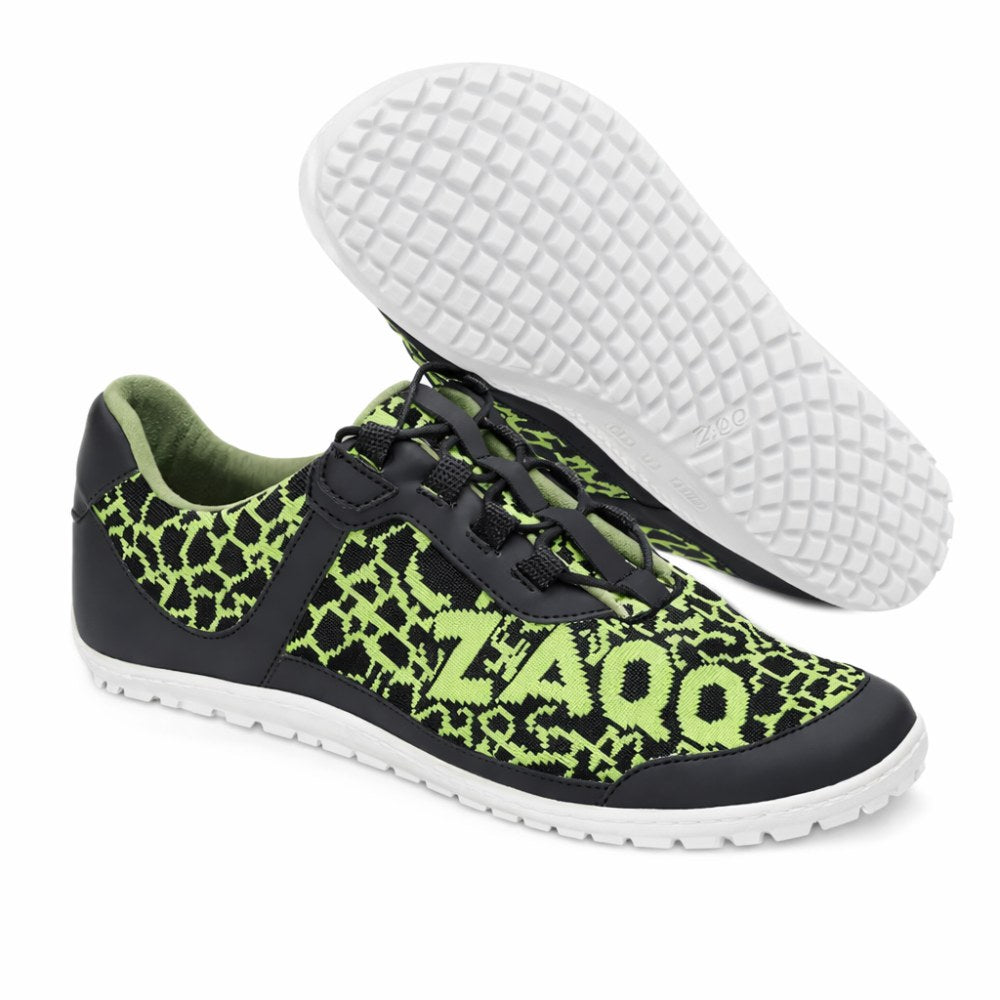 Wir präsentieren den QASEY Green von ZAQQ: ein Paar Freizeitschuhe mit einem auffälligen schwarz-grünen Musterdesign aus veganen Materialien. Die Schuhe zeigen das ZAQQ-Logo deutlich sichtbar an der Seite. Sie sind mit einer klassischen weißen Sohle mit Barfußschuhstruktur für besseren Halt ausgestattet. Ein Schuh ist aufrecht stehend abgebildet, während der andere auf der Seite liegt, um das einzigartige Sohlendesign zu präsentieren.
