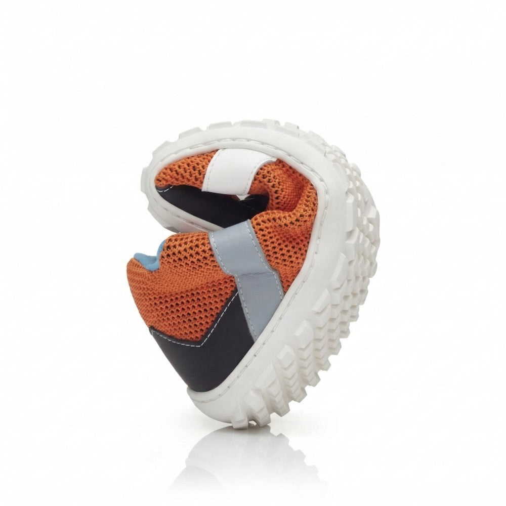 Der ZARQA Orange von ZAQQ ist ein flexibler, moderner Sneaker, der seine Vielseitigkeit mit einer klobigen Sohle zeigt, die gebogen ist, um seine Runningschuh-Funktionalität zu betonen. Er besticht durch ein lebendiges Design mit orangefarbenem Mesh mit blauen und schwarzen Akzenten, ergänzt durch einen weißen Streifen. Die Sohle weist ein strukturiertes grau-weißes Muster auf.